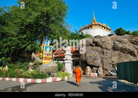 Un moine marchant dans les motifs de Wat Saket, Bangkok, Thaïlande, le Mont d'or dans l'arrière-plan, avant-plan : un portrait du roi Maha Vajiralongkorn Banque D'Images