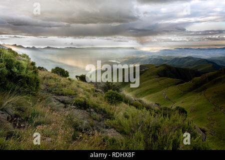 La lumière du soleil par des nuages épais à la lumière de la pluie sur une région éloignée de l'amphithéâtre du Drakensberg paysage, sentier de randonnée, NP Royal Natal, SA Banque D'Images