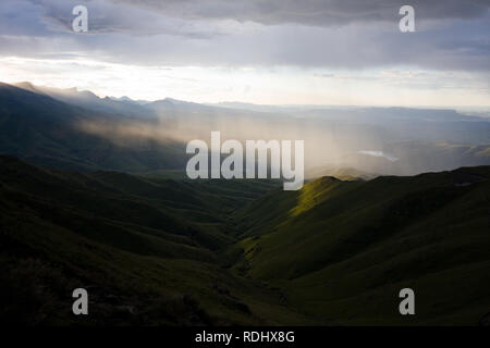 La lumière du soleil par des nuages épais à la lumière de la pluie sur une région éloignée de l'amphithéâtre du Drakensberg paysage, sentier de randonnée, NP Royal Natal, SA Banque D'Images