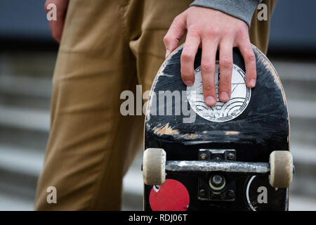 Skater hand holding skateboard pont dans un environnement urbain en plein air Banque D'Images