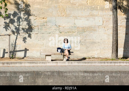 Une femme est assise sur le banc par le canal St-Martin à Paris, France. Banque D'Images