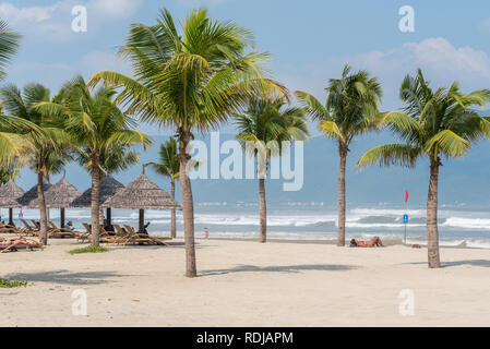 Danang, Vietnam - 1 novembre 2018 : China Beach avec plusieurs arbres de noix de coco, paille de parasols et bains de soleil plusieurs touristes. Banque D'Images