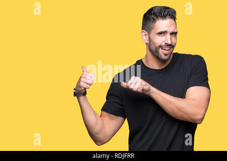 Jeune homme séduisant sur fond isolé en pointant sur l'arrière derrière avec la main et Thumbs up, souriant confiant Banque D'Images