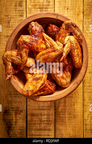 Ailes de poulet grillés délicieux dans bol en bois sur la vieille table en bois. Banque D'Images