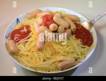 La plaque avec le ketchup spaghetti, fromage et saucisses cocktail rasée. Banque D'Images