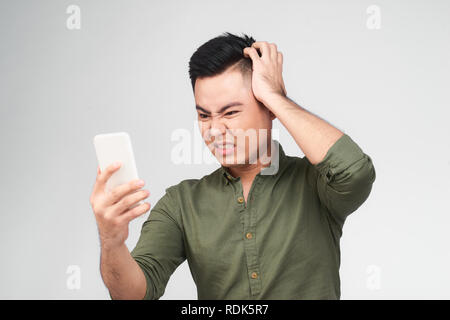 Portrait de las male student isolated on white la lecture d'articles, de faire des travaux à la recherche d'informations dans Internet à l'aide de son smartphone. Troublant Banque D'Images