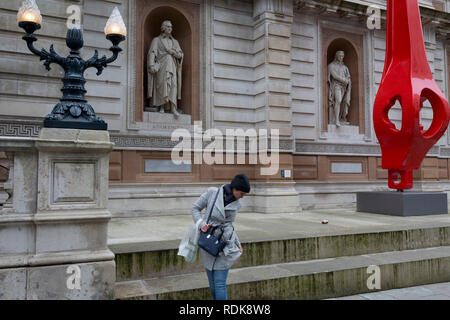 Une femme vérifie ses vêtements après avoir siégé sous la statue du philosophe victorienne britannique John Locke (par William Theed) et une sculpture moderne par Renzo Piano, avec une reproduction d'une fibre de verre "gerberette', l'une des poutres en die-cast de couvre-culasse de cantilever que Georges Pompidou de Paris, le 10 janvier 2019, à Londres, en Angleterre. Le philosophe britannique John Locke (1632 - 1704) dont les effigies sont par William Theed, également connu sous le nom de William Theed, le jeune (1804 - 9 septembre 1891) un sculpteur anglais dont les services ont été largement utilisées par la famille royale. Banque D'Images