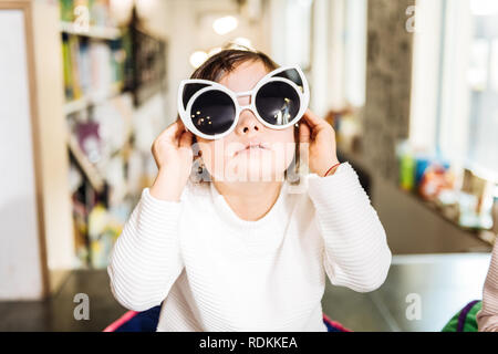 Drôle de petite fille avec le syndrome de s'amuser avec des lunettes Banque D'Images