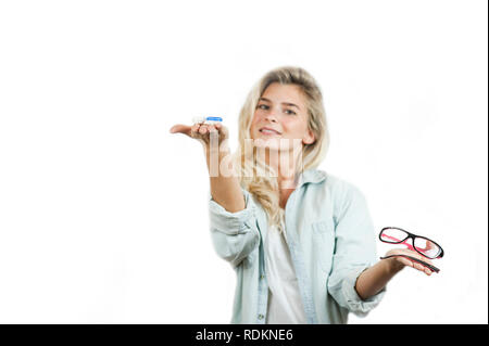 Très belle jeune fille fait un choix entre lunettes et lentilles cassées sur un cas isolé sur fond blanc Banque D'Images