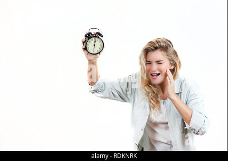 Très belle fille fatigué par des maux de tête du fait que le réveil sonne et il est temps de se lever sur un fond isolé blanc Banque D'Images