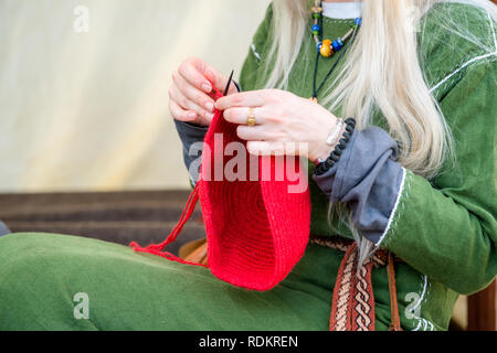 Close-up of woman knitting mains chapeau en laine rouge, tout en portant des vêtements de lin en milieu rural. Offres de travail et de vie créative concept Banque D'Images