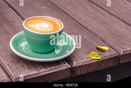 Latte Cup Turquoise sur un fond de bois avec des coeurs d'or. La vie toujours à la Saint-Valentin. Banque D'Images