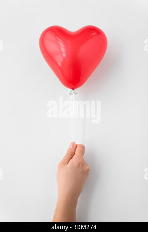 Close up of hand holding red heart shaped balloon Banque D'Images