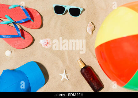 Cap, tongs et de nuances et de ballons de plage sur le sable Banque D'Images