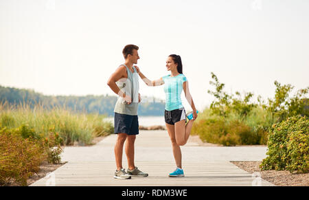 Smiling couple stretching jambes on beach Banque D'Images