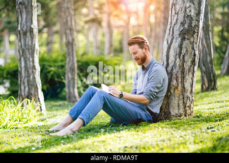 Handsome businessman using tablet pc in park Banque D'Images