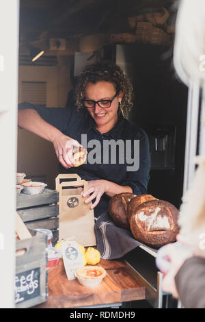 Smiling woman wearing glasses fraîchement mise à tarte cuite dans du papier brun panier. Banque D'Images