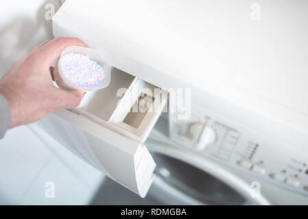 Personne à l'aide de l'aide à la posologie pout lessive en poudre dans un lave-linge Banque D'Images