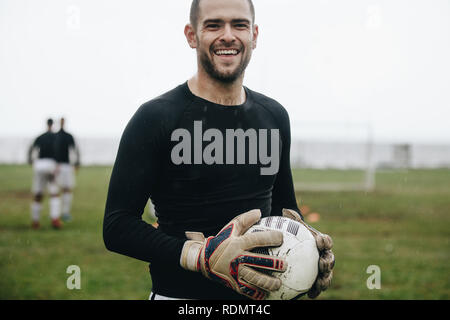 Libre de gardien debout avec un ballon de foot dans la main. Joueur de football sur terrain permanent holding a football pratiquer le matin. Banque D'Images
