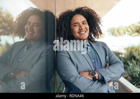 Young mixed race guy avec curly afro à la caméra dans les bras croisés et sourire Banque D'Images