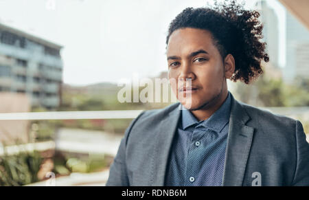 Les jeunes confiants mixed race guy avec afro bouclés à la recherche dans l'appareil photo, avec copie espace Banque D'Images