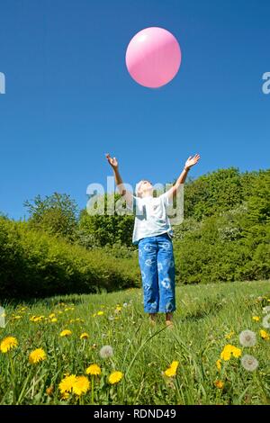 Fille essayant d'attraper un gros ballon rose Banque D'Images