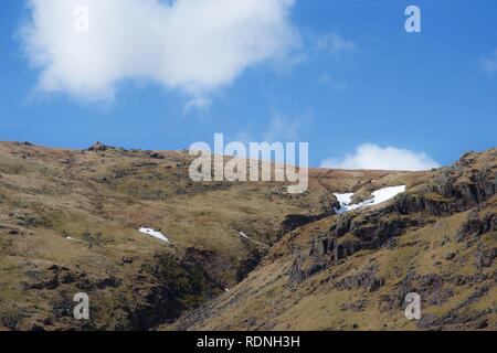 Vallée escarpée entre crags : Ruisseau de montagne (Beck) entre les rochers et les landes herbeuses. Ciel bleu avec des nuages blancs, escarpés et plusieurs sommets de montagnes. Sn Banque D'Images