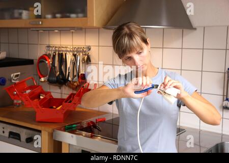 Jeune femme de la réparation d'une fiche du câble d'alimentation Banque D'Images