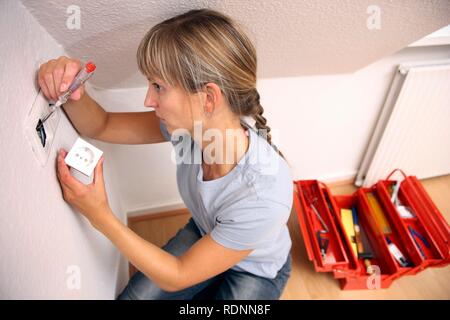 Jeune femme de l'installation d'une prise de courant Banque D'Images