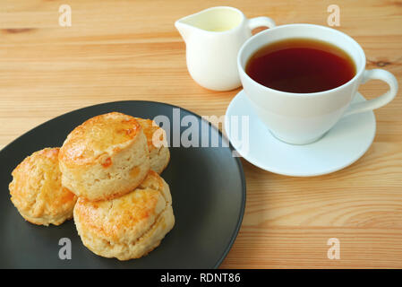 Une plaque d'orange confites scones et une tasse de thé chaud servi sur table en bois Banque D'Images