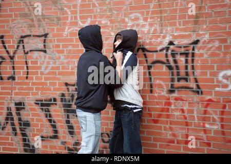 Un petit garçon adolescent poussant violemment contre un mur de scène, pose Banque D'Images