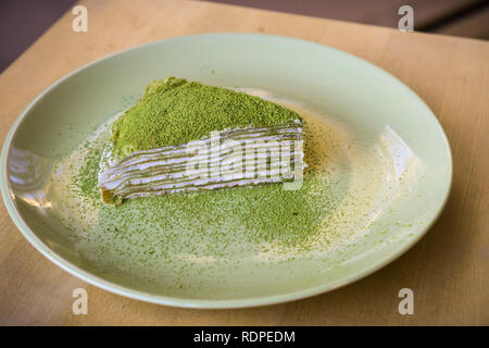 Tranche de gâteau crêpe mille Matcha fait maison recouvert de poudre de thé vert pour les fins de la présentation Banque D'Images