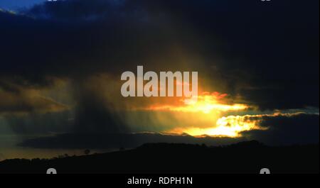 Incroyable coucher du soleil avec la pluie et l'oiseau en vol. Des faisceaux de lumière. Plus de Dartmoor, dans le Devon. Banque D'Images