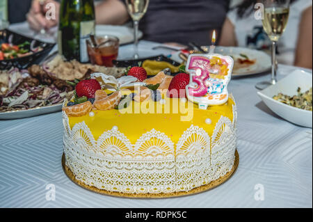 Brûler des bougies sur un gâteau avec des baies à une fête pour les enfants. Les fraises et les bleuets pour un délicieux dessert. focus sélectif. Banque D'Images