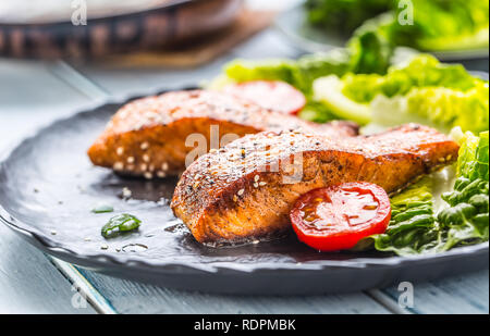 Délicieux grillés filets ou darnes de saumon rôti au sésame salade de laitue et tomates. Banque D'Images