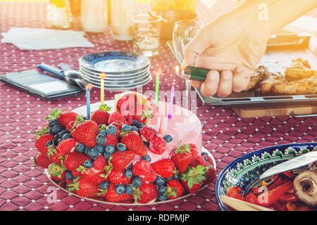 Brûler des bougies sur un gâteau avec des baies à une fête pour les enfants. Les fraises et les bleuets pour un délicieux dessert. selective focus Banque D'Images