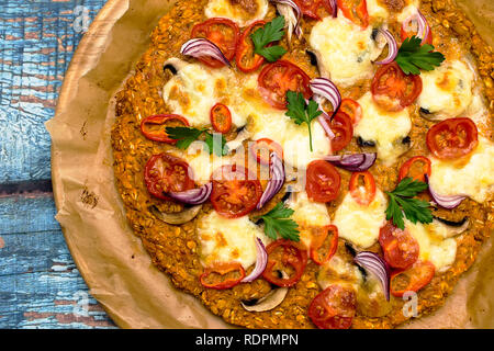 Pizza avec blat de patate douce et de graines d'avoine, garnie de champignons, oignons, mozzarella et tomates cerises Banque D'Images