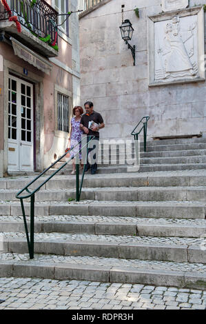 Un couple walking down steps dans les ruelles d'Alfama, Lisbonne, Portugal Banque D'Images