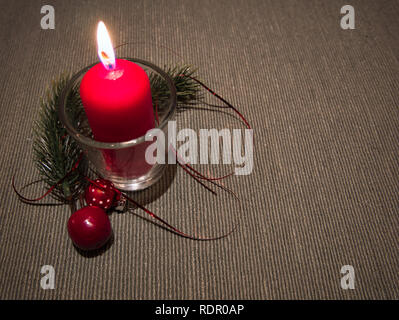 Une bougie rouge dans un verre sur la table avec décoration Banque D'Images