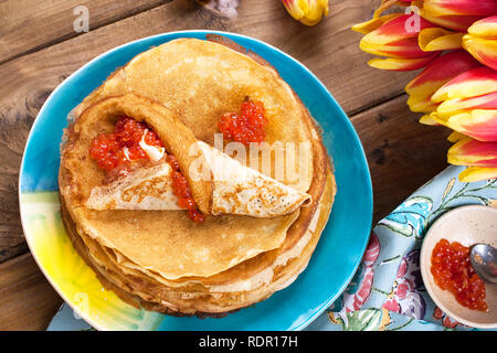 Crêpes de caviar et de beurre, un bouquet de tulipes et un fond de bois. Cuisine russe traditionnelle pour le carnaval. Vue d'en haut Banque D'Images