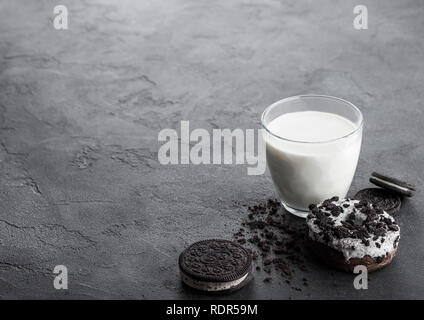 Verre de lait et biscuits sandwich noir avec anneau et glace sur pierre noire table de cuisine arrière-plan. Banque D'Images