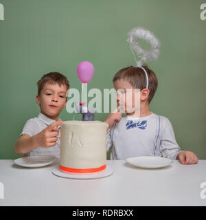 Deux garçons lécher un gâteau à la crème. Deux garçons vêtus de blanc manger tarte d'anniversaire avec les mains. Gâteau d'anniversaire. Sweet table pour les enfants. La nourriture bonne idée. Ador Banque D'Images