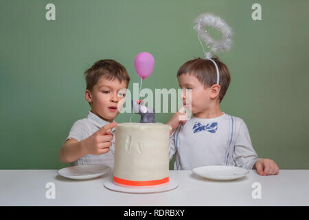 Fiche société de confiserie. Gâteau d'anniversaire. Célébrer la première pâtisserie anniversaire noël. Deux garçons lécher un gâteau à la crème. Deux garçons vêtus de blanc manger Banque D'Images