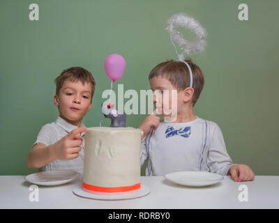 Deux garçons lécher un gâteau à la crème. Deux garçons vêtus de blanc manger tarte d'anniversaire avec les mains. Sibligns Jour de célébration. Parti frère nouveau-né célébration. Banque D'Images