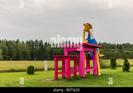 Vilnius, Lituanie - 8 septembre 2018 : en bois géant Buratino (Pinocchio) assis à l'énorme réfléchissant table rose dans le parc. Banque D'Images