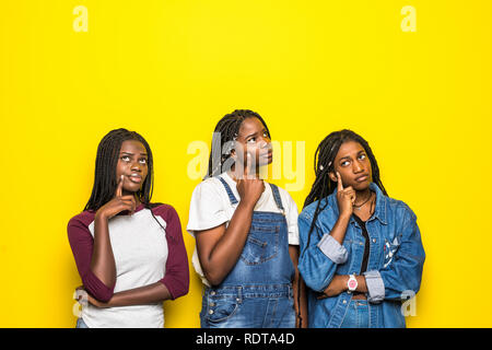 Portrait de groupe de trois belles femmes africaines with hand on chin pense à question, pensive expression sur fond jaune. On Beach Banque D'Images