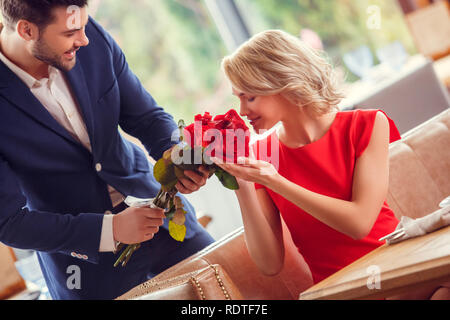 Jeune couple sur la date dans le couple gai bouquet donnant à woman smelling buds heureux Banque D'Images