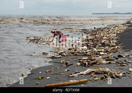 Les personnes qui reçoivent des déchets à Bali Beach pendant la mousson Banque D'Images