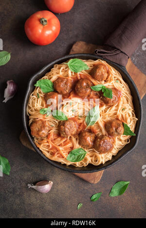 Les pâtes Spaghetti aux Boulettes de viande, sauce tomate et basilic frais dans la poêle en fonte. Les pâtes italiennes faites maison saine sur fond rustique avec copie espace. Banque D'Images