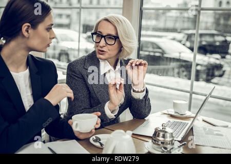 Aux cheveux Blond businesswoman giving quelques instructions à son stagiaire Banque D'Images